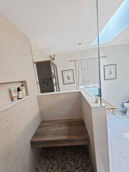 Renovated bathtub and shower area beneath a skylight