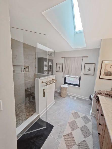 Glass shower enclosure in a bright bathroom with a skylight