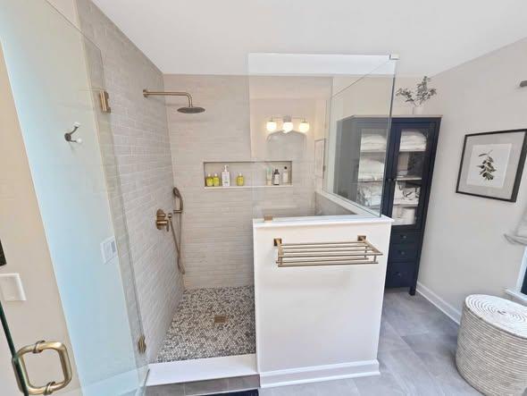 Walk-in shower with a bench, niche, and pebble tile floor